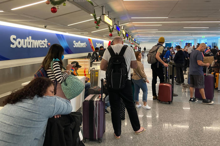 Travelers wait at a Southwest Airlines baggage counter after flight cancellations hit Los Angeles International Airport on Monday. The airline warns it will fly about one-third of its schedule for the next several days.