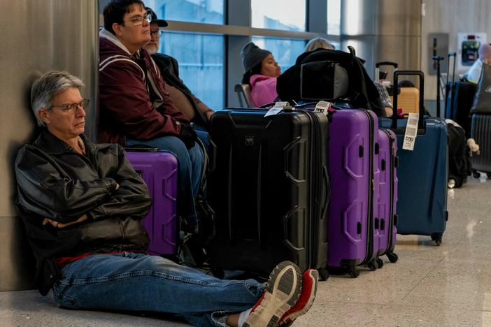 Travelers wait next to their luggage near the Southwest Airlines baggage claim area at the Nashville International Airport after the airline canceled thousands of flights in Nashville, Tenn., on Tuesday.