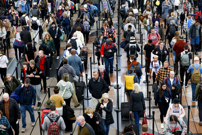Travelers wait in line before passing through a security checkpoint at Denver International Airport on December 28, 2022 in Denver, Colorado.
