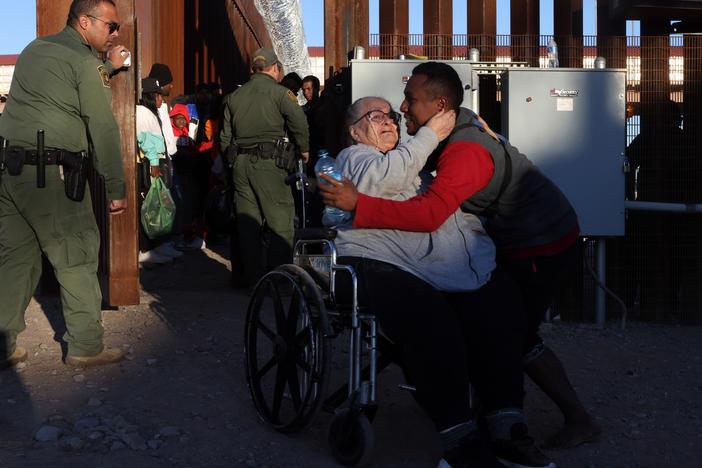 An asylum-seeking migrant woman from Peru in a wheelchair is escorted through the border wall to be processed by U.S. Customs and Border Protection after crossing the Rio Grande into the United States in El Paso, Texas, on Dec. 21.