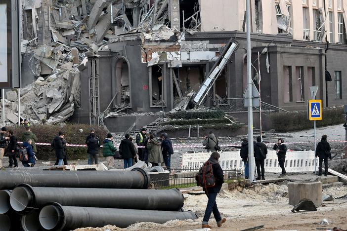 People gather at the bottom of a hotel, which has been partially destroyed by a Russian strike in the center of the Ukrainian capital Kyiv on Saturday.