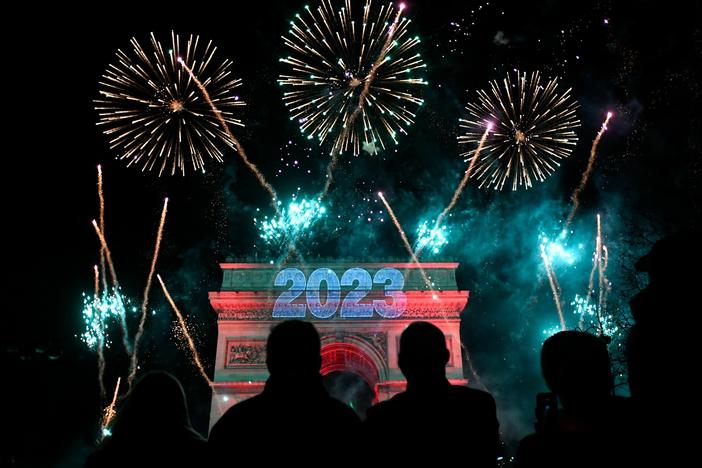 Fireworks explode next to the Arc de Triomphe with "2023" projected on the building, at the Avenue des Champs-Elysees during New Year celebrations in Paris.