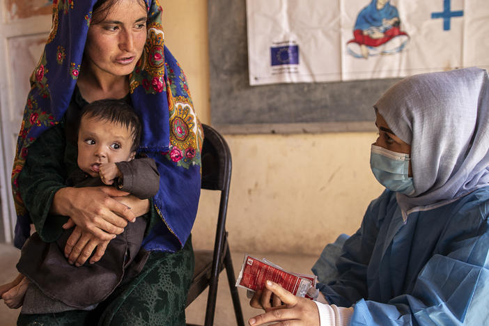 A Save the Children nutrition counsellor, right, explains to Nelab, 22, how to feed her 11-month-old daughter, Parsto, with therapeutic food, which is used to treat severe acute malnutrition, in Sar-e-Pul province of Afghanistan in September 2022.