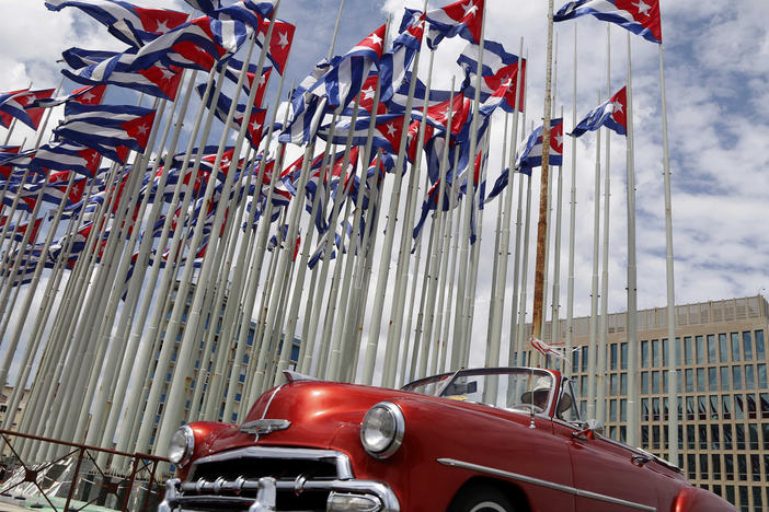 A classic American convertible car passes beside the United States embassy as Cuban flags fly at the Anti-Imperialist Tribune, a massive stage on the Malecon seaside promenade in Havana, Cuba, July 26, 2015.