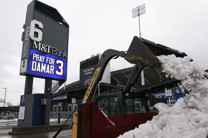 Crews clear snow from a parking lot near a sign showing support for Buffalo Bills safety Damar Hamlin outside Highmark Stadium on Wednesday in Orchard Park, N.Y.
