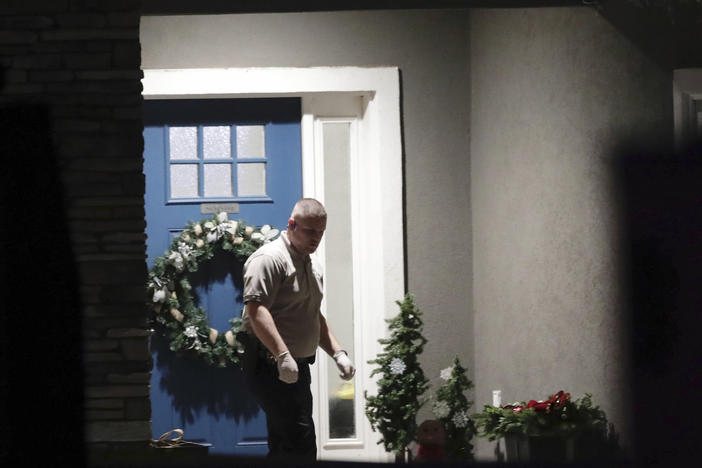 A law enforcement official stands near the front door of the Enoch, Utah, home where eight family members were found dead from gunshot wounds, Wednesday, Jan. 4, 2023.