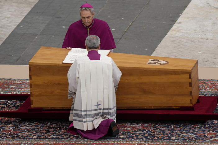 Archbishop Georg Ganswein kneels by the coffin of late Pope Emeritus Benedict XVI is brought to St. Peter's Square for a funeral mass at the Vatican, Thursday, Jan. 5, 2023.