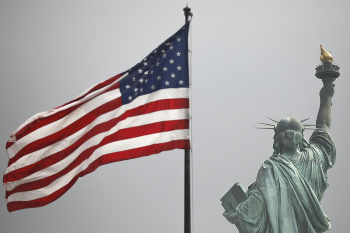An America flag flies near the Statue of Liberty on Liberty Island.