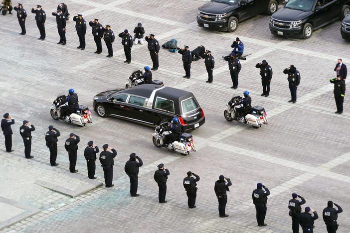 The hearse carrying the remains of Capitol Police officer Brian Sicknick drives past police officers saluting after a funeral ceremony at the US Capitol February 3, 2021 in Washington, DC.
