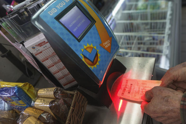 Roberto Ramirez checks his SuperLotto Plus ticket Friday at a gas station in Altadena, Calif.