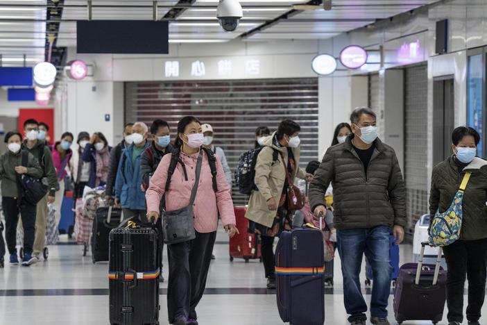 Travelers wearing face masks with their luggage head to the immigration counter at the departure hall at Lok Ma Chau station following the reopening of crossing border with mainland China, in Hong Kong, Sunday, Jan. 8, 2023.