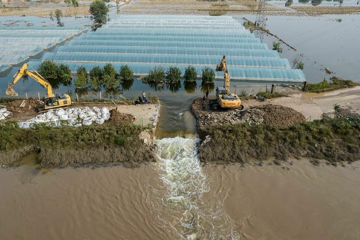 Rescuers dig a spillway to release flood waters after heavy rainfall in China's northern Shanxi province in 2021. A new report finds that human-caused climate change made the floods about twice as likely.
