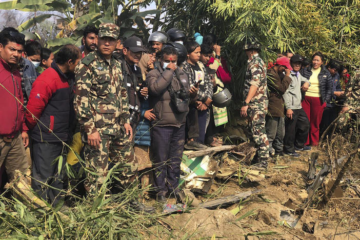 Locals watch the wreckage of a passenger plane in Pokhara, Nepal, Sunday, Jan.15, 2023. A passenger plane with 72 people on board has crashed near Pokhara International Airport in Nepal, the daily newspaper Kathmandu Post reports. The plane was carrying 68 passengers and four crew members.
