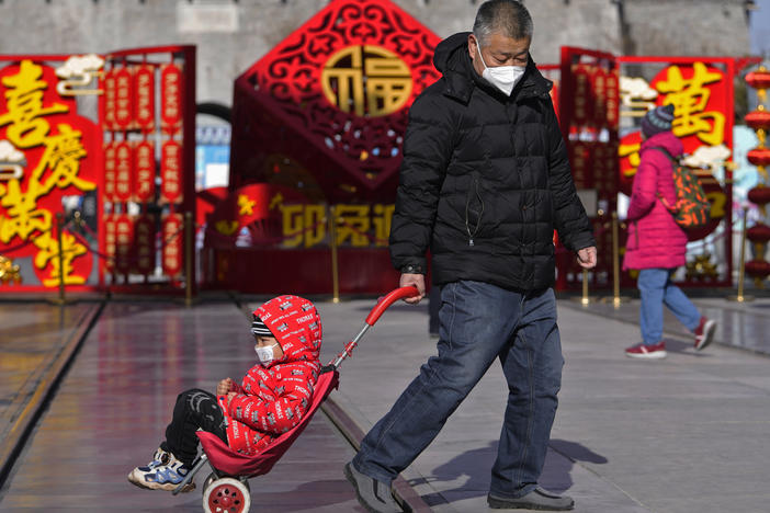 A man pulls a child past a Lunar New Year decoration on display at the Qianmen pedestrian shopping street, a popular tourist spot in Beijing, on Tuesday.