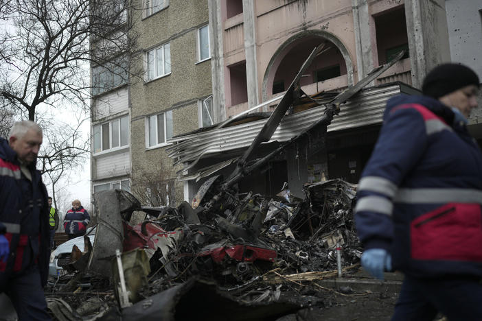 Workers pass the scene where a helicopter crashed in Brovary, on the outskirts of Kyiv, Ukraine, Wednesday. The chief of Ukraine's National Police says the crash in a Kyiv suburb has killed 18 people, including Ukraine's interior minister and two children.