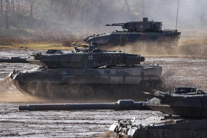 Two Leopard 2 A6 heavy battle tanks and a Puma infantry fighting vehicle of the Bundeswehr's 9th Panzer Training Brigade participate in a demonstration of capabilities during a visit by then-Defense Minister Christine Lambrecht to the Bundeswehr Army training grounds in February 2022 in Munster, Germany.