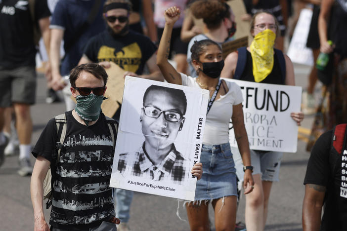 Demonstrators carry placards during a rally and march on June 27, 2020, over the death of Elijah McClain in Aurora, Colo.