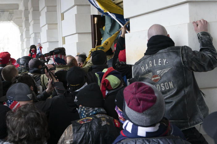Rioters try to open a door of the U.S. Capitol on Jan. 6, 2021. Three active-duty Marines have been charged in the attack.