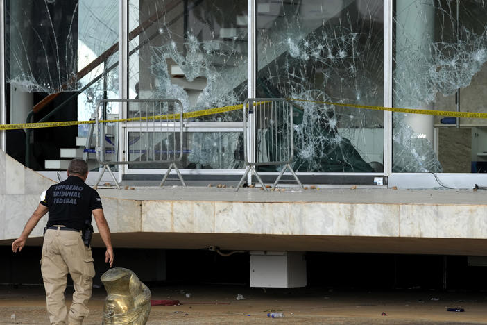 An agent walks past the head of a statue depicting the Greek goddess Themis, outside the Brazilian Supreme Court building that was damaged by supporters of Brazil's former President Jair Bolsonaro, in Brasilia, Brazil, Tuesday, Jan. 10, 2023.