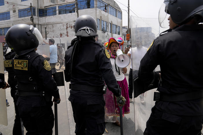 An anti-government protester challenges police surrounding the San Marcos University in Lima, Peru, Saturday, Jan. 21, 2023. Police evicted from the university grounds protesters who arrived from Andean regions seeking the resignation of President Dina Boluarte, the release from prison of ousted President Pedro Castillo and immediate elections.