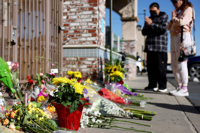 People stand at a makeshift memorial near the scene of the shooting.