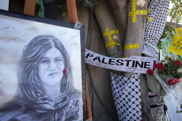 Yellow tape marks bullet holes on a tree and a portrait and flowers create a makeshift memorial, at the site where Palestinian-American Al-Jazeera journalist Shireen Abu Akleh was shot and killed in the West Bank city of Jenin, May 19, 2022.