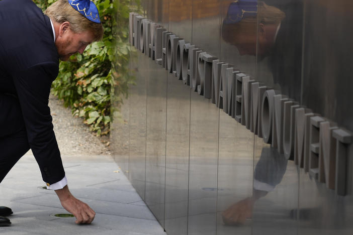 King Willem-Alexander puts a stone in an act of remembrance when unveiling a new monument in the heart of Amsterdam's historic Jewish Quarter on Sept. 19, 2021, honoring the 102,000 Dutch victims of the Holocaust.
