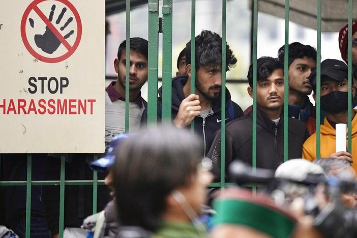 Students watch security personnel guard the main gate of Jamia Millia Islamia university Wednesday in New Delhi, India. A student group said it planned to screen a banned documentary that examines Indian Prime Minister Narendra Modi's role during 2002 anti-Muslim riots, prompting dozens of police equipped with tear gas and riot gear to gather outside campus gates.