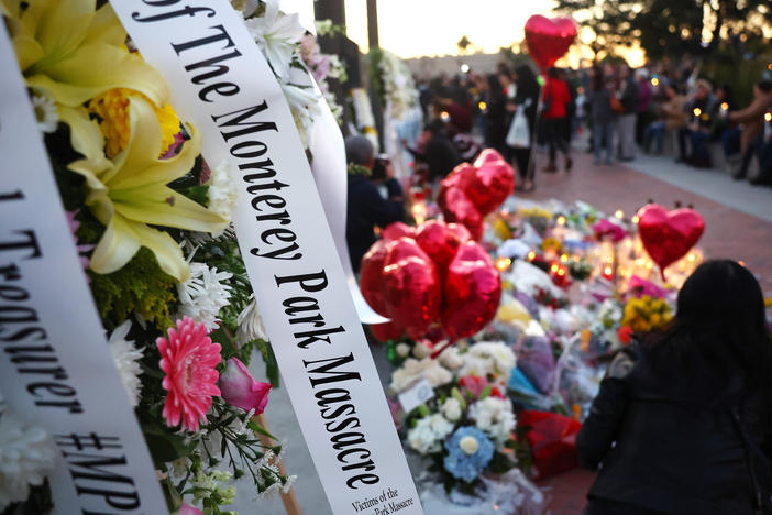 People gather at a memorial for the victims of a mass shooting over the weekend at a ballroom dance studio in Monterey Park, Calif.