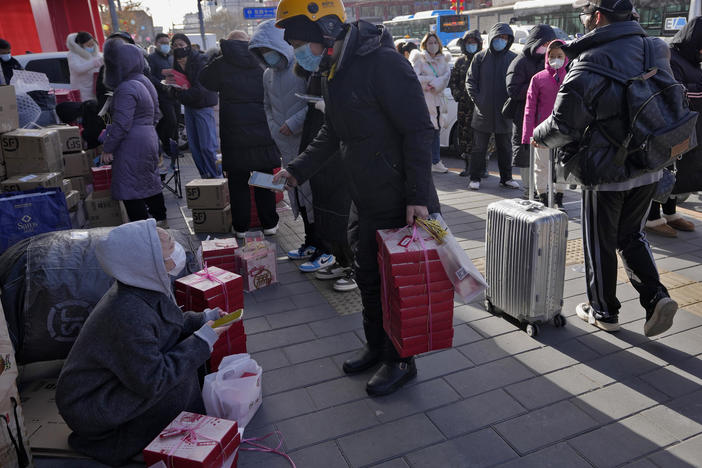 A delivery rider picks up his customers' online order as residents line up outside a store to buy Lunar New Year desserts in Beijing, Jan. 17. China's economic growth fell to its second-lowest level in at least four decades last year under pressure from anti-virus controls and a real estate slump.