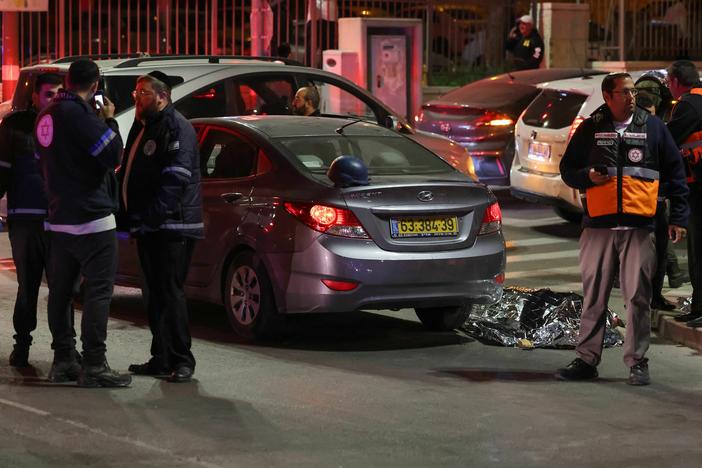 Israeli emergency service personnel and security forces stand near a covered body at the site of a reported attack in Jerusalem on Friday.