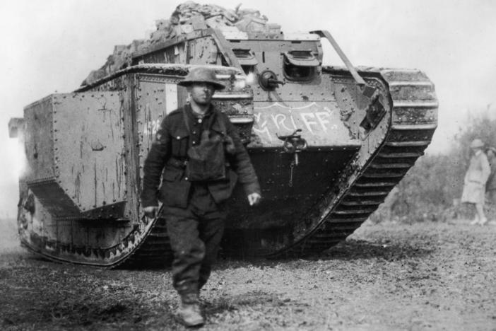 An American soldier walks ahead of an MKIV British-made tank, circa 1918.