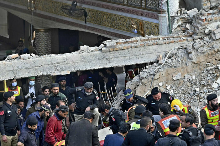 Security officials and rescue workers search for bodies Monday at the site of suicide bombing, in Peshawar, Pakistan.