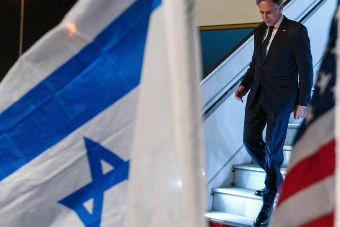 U.S. Secretary of State Antony Blinken walks by U.S. and Israeli flags upon arrival to Ben Gurion airport near Tel Aviv.