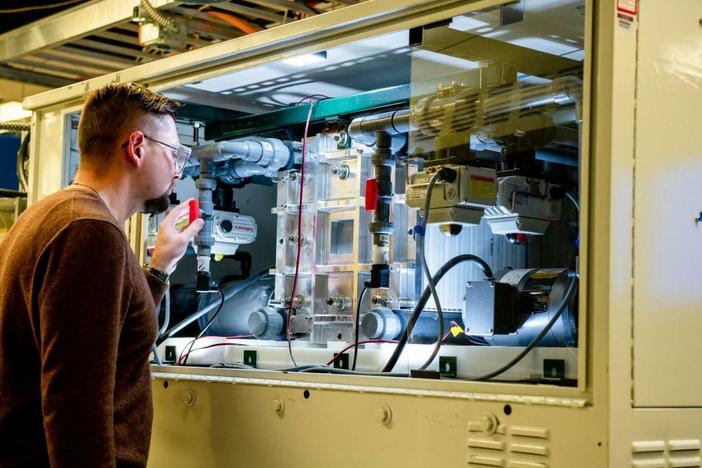 An employee examines a vanadium flow battery stack in the Battery Reliability Test Laboratory at PNNL.