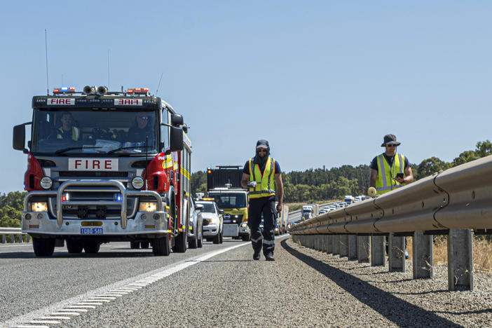 In this photo provided by the Department of Fire and Emergency Services, its members search for a radioactive capsule believed to have fallen off a truck being transported on a freight route on the outskirts of Perth, Australia, on Saturday.