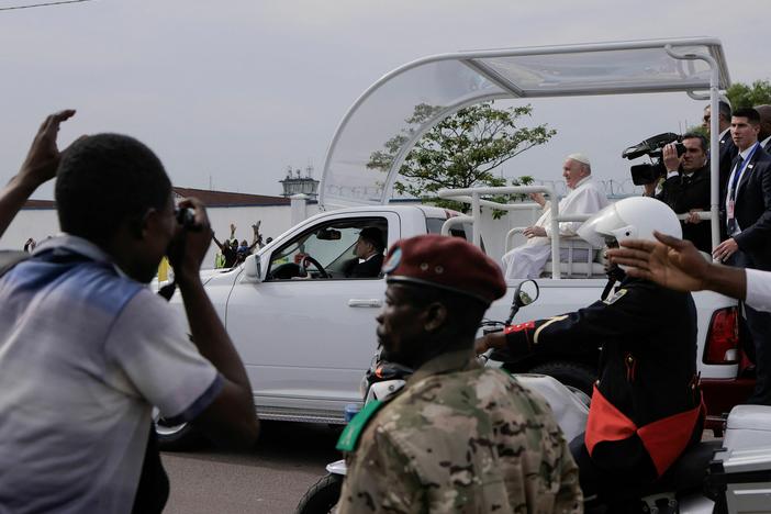 Bystanders look on as Pope Francis travels by popemobile as he departs the airport in the Democratic Republic of Congo.