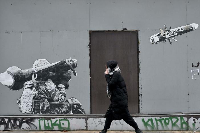A woman walks past graffiti depicting a Ukrainian soldier firing a missile, in Kyiv on Jan. 25. The Russians are fighting an intense air war, but it involves mostly missiles, drones and anti-aircraft system. Traditional air strikes by piloted war planes have been relatively rare.