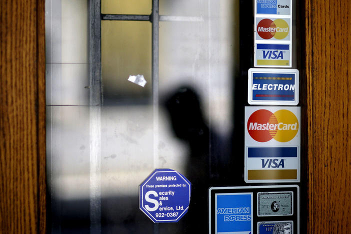 Credit card logos are seen on a downtown storefront as a pedestrian passes in Atlanta in 2012.