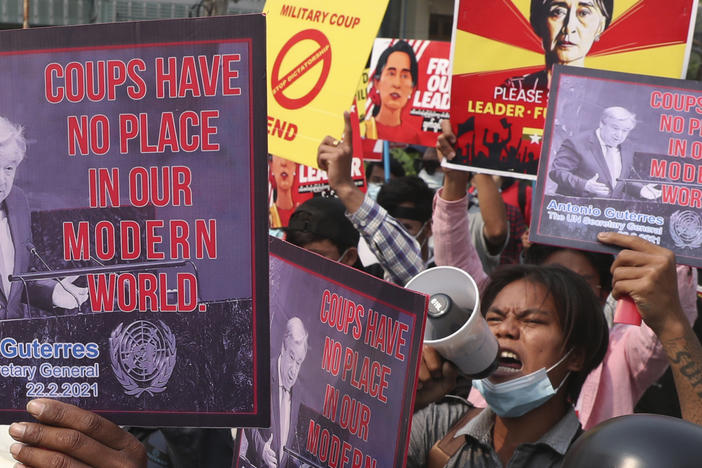 Anti-coup protesters hold up signs as they march in Mandalay, Myanmar Sunday, March 14, 2021. The prospects for peace in Myanmar, much less a return to democracy, seem dimmer than ever two years after the army seized power from the elected government of Aung San Suu Kyi, experts say.