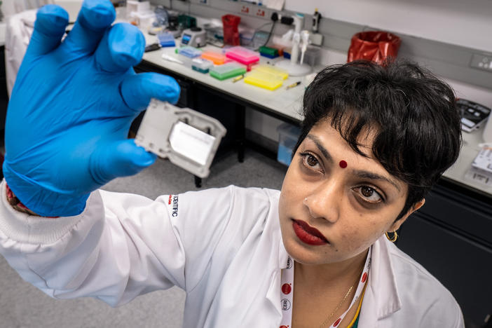 Yeshnee Naidoo prepares a "flow cell" for analysis by one of the center's many genetic sequencing machines.