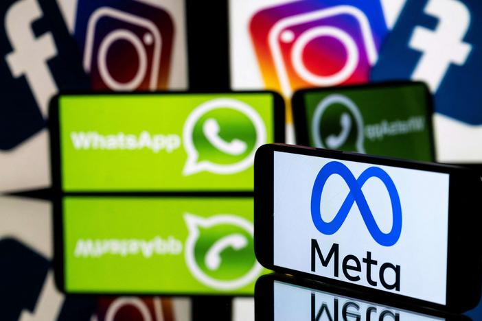 This picture taken on January 12, 2023 in Toulouse, southwestern France shows a smartphone and a computer screen displaying the logos of the Instagram, Facebook, WhatsApp and their parent company Meta.