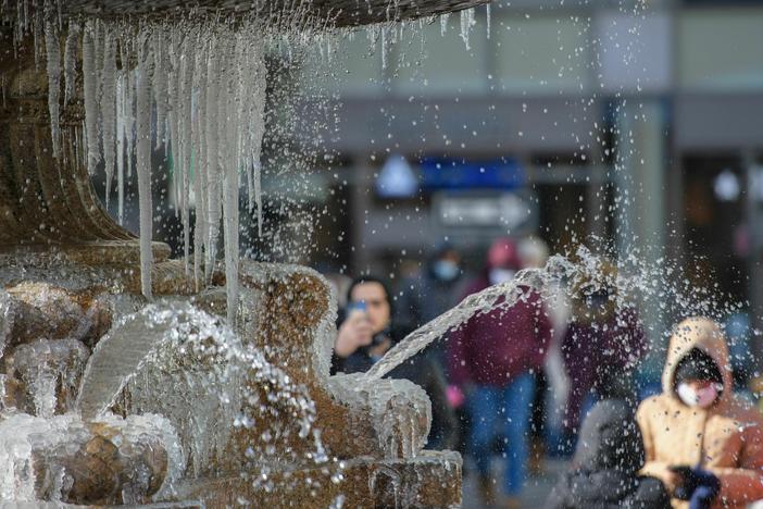 Pedestrians view a partially frozen fountain on a cold-weather day on Jan. 11 in New York City.
