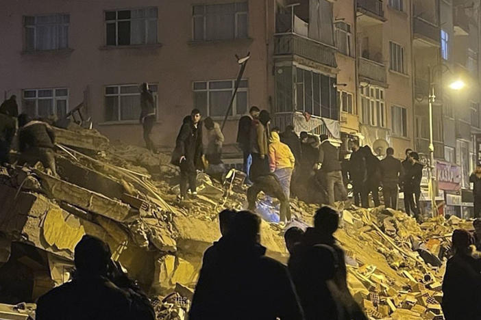 People try to reach trapped residents in a collapsed building in Pazarcik, in Kahramanmaras province, southern Turkey, early Monday, Feb. 6, 2023.