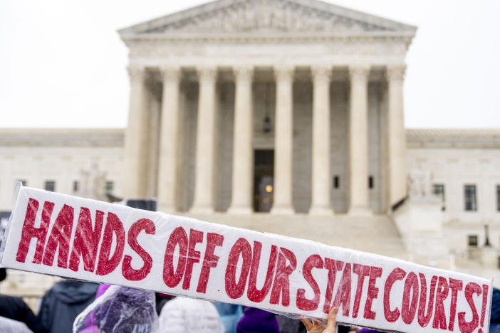 A demonstrator holds up a sign that reads "HANDS OFF OUR STATE COURTS!" during a December 2022 rally in front of the U.S. Supreme Court in Washington, D.C.
