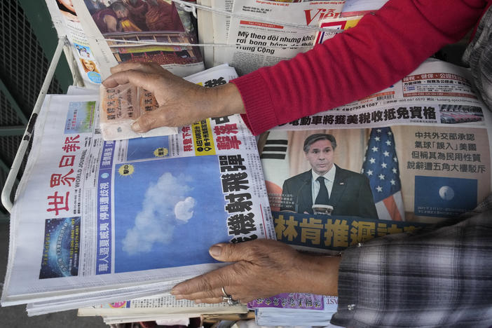 Business owner "Annie" weights down copies of the Chinese Daily News newspaper showcasing pictures of a suspected Chinese spy balloon, in the Chinatown district of Los Angeles Sunday, Feb. 5, 2023.