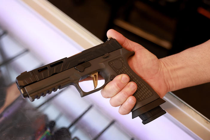 A Sig Sauer P320 handgun is held at a store.
