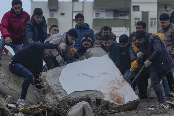 Men search for people among the debris in a destroyed building in Adana, Turkey, Monday.