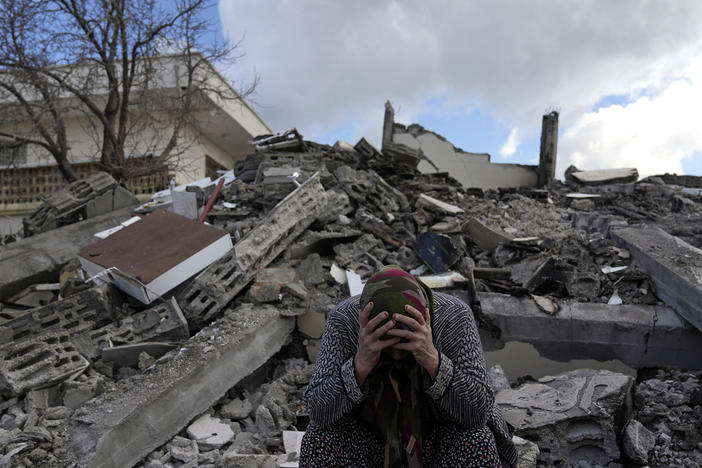 A woman sits on the rubble as emergency rescue teams search for people under the remains of destroyed buildings in the town of Nurdagi on the outskirts of Osmaniye in southern Turkey on Tuesday.