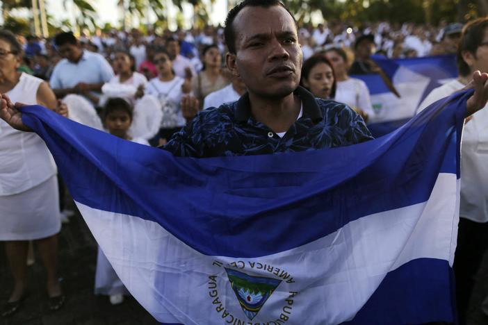 A man holds a Nicaraguan flag in favor of peace in Nicaragua.